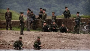 Північнокорейські військові в камуфляжі біля річки та бетонної огорожі