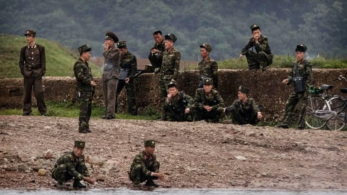 Північнокорейські військові в камуфляжі біля річки та бетонної огорожі